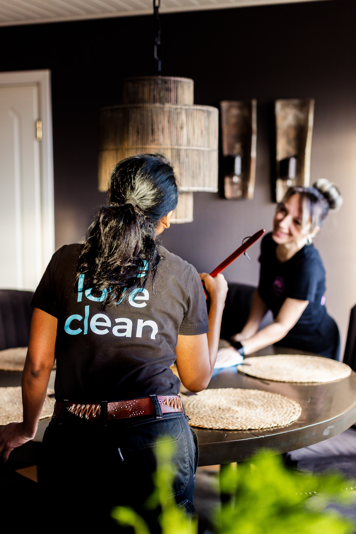 hemstadning-fixclean-stadforetag Två kvinnor från Fix Clean som utför hemstädning. De står på var sin sida av ett köksbord och skrattar mot varandra.